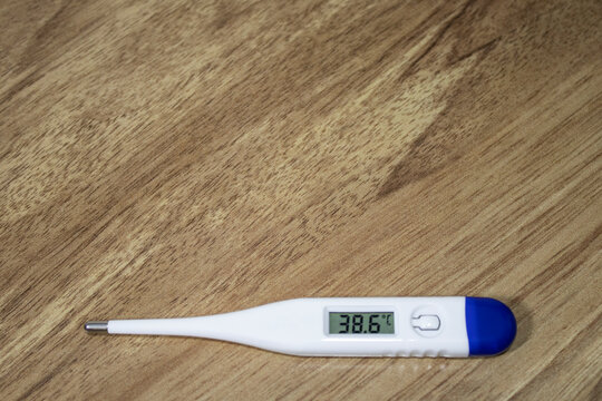 Thermometer showing high fire view on wooden table. Thermometer with 38 degree indicator with blue handle.