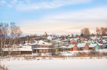 Fototapeta premium Wooden houses on the banks of the snow-covered Shokhonka River in Plyos