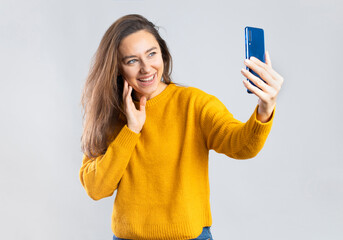 Portrait of cheerful girl smiling and taking selfie using mobile phone