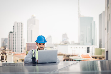 Smart engineer maintenance in solar power plant checking installing photovoltaic solar modules with laptop and using walkie talkie. Concept of sustainable resources, saving energy.