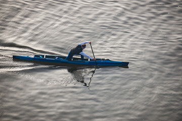 Prague, Czech republic - February 24, 2021. Aerial view of young man sailing on blue single canoe in canoe sprint in sunset © marketanovakova