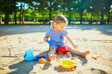 Adorable little girl having fun on playground in sandpit