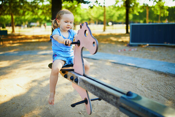 Adorable little girl having fun on seesaw