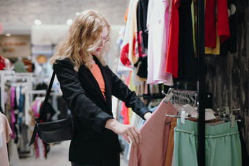 Woman chooses a clothes in the store before buying