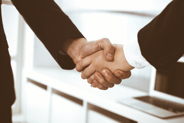 Businessman and woman shaking hands in office. Concept of handshake as success symbol in business