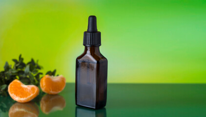 Mandarin oil. Brown bottle with a pipette on a green background.
