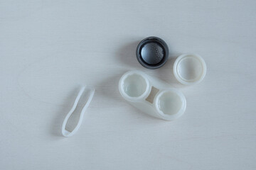 Open container with contact lenses, tweezers. Correction of vision.