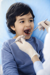 Little arab boy sitting at dental chair with open mouth during oral checking up with dentist doctor. Stomatology concept