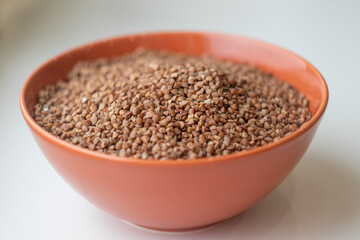 dry buckwheat in a brown bowl close-up