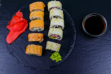 Set of sushi rolls on a black stone slate. Top view