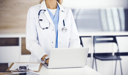 Unknown female physician using laptop computer, close-up. Woman-doctor at work in clinic. Medicine concept