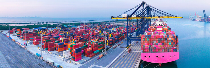 Aerial view over international containers cargo ship at industrial import-export port prepare to...