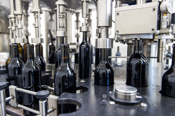 Red wine bottles being processed at winery bottling factory
