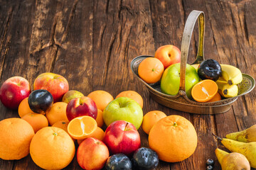 Healthy fruit on a wooden background. Stylish, ornate metal basket full of fresh fruit. Place for text