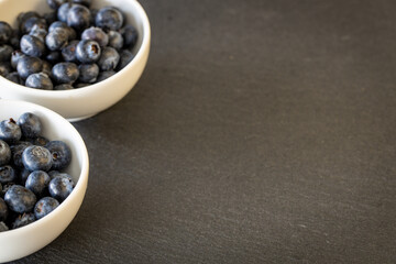 Fresh and healthy blueberries in bowls standing on a stone counter. Place for your own inscription