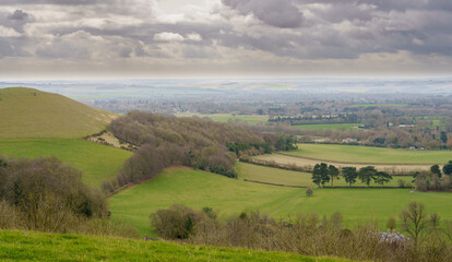 Fototapeta na wymiar scenic Southerly view over Oare and across the Pewsey Vale valley with green pastures and a cloudy light grey sky