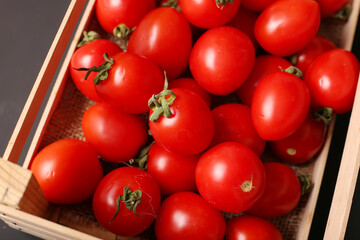 Ripe tomatoes in a wooden box. On a wooden table.