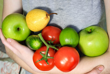 Women's hands hold various fruits and vegetables in a pile.