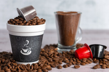 Distintos tipos de cafe, crudo, tostado, molido y en capsulas en varios recipientes.