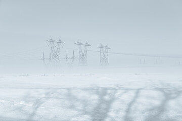 View of power line towers in farmland fields during a beautiful foggy late winter early morning, Levis, Quebec, Canada