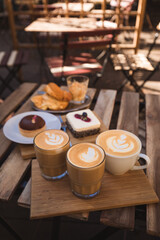 hipster wooden table full of coffee, cappuccino and flat white and desserts ready for customer