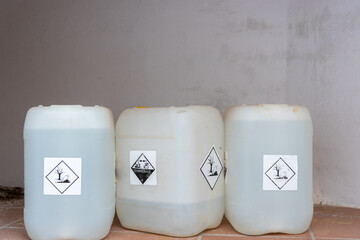 Bottles or jerricans with corrosive and harmful liquids for the environment, danger labels according to the international agreement on dangerous goods (ADR).