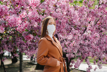 A young girl takes off her mask and breathes deeply after the end of the pandemic on a Sunny spring...