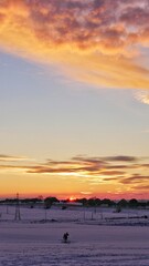 silhouette of person sledding through the snow at sunset