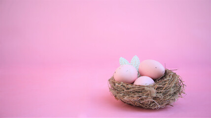 Easter composition with eggs and rabbit ears made of small pearls on pink pastel background.