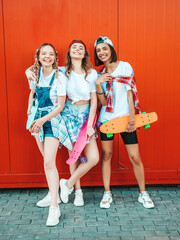 Three young smiling beautiful female with colorful penny skateboards.Women in summer hipster...