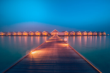 Amazing sunset panorama at Maldives. Luxury resort hotel villas seascape with soft led lights under colorful sky. Ocean lagoon, stunning romantic skyscape, seascape. Relax inspirational vacation beach