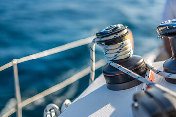 Closeup details of sailing winch equipment on a boat when sailing on the water in a sunny day. Sailboat sailing template in blue ocean sea - obrazy, fototapety, plakaty