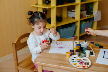 A cute little girl is playing and painting in her room. Recreation and entertainment