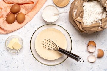 the process of making dough for pancakes with ingredients on a light table, eggs and flour are whipped with a mixer