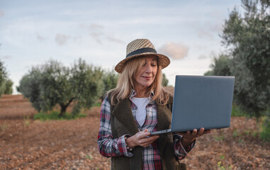 Female field engineer using computer in agricultural plantation. Integration of women in the field, agriculture and happy women concepts