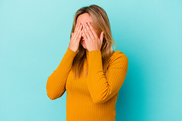 Young mixed race woman isolated on blue background afraid covering eyes with hands.