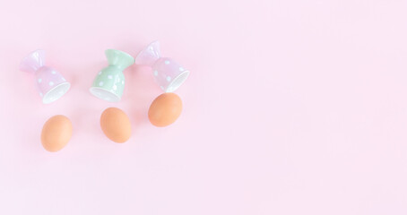 Easter eggs on pink background. Eggs and colourful egg cups. Pastel colors table decor.