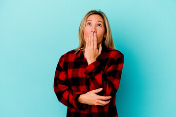 Young mixed race woman isolated on blue background yawning showing a tired gesture covering mouth with hand.