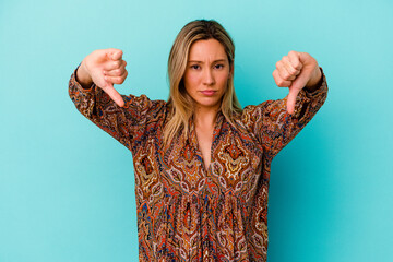 Young mixed race woman isolated on blue background showing a dislike gesture, thumbs down....