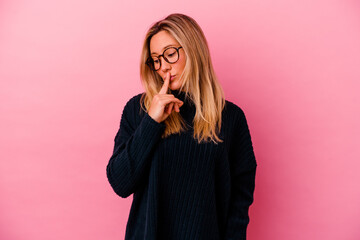 Young mixed race woman isolated on pink background keeping a secret or asking for silence.