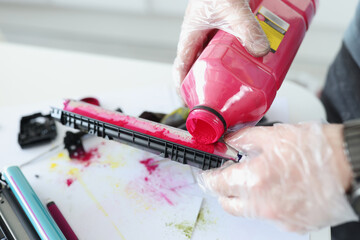 Technician pours red ink into cartridge closeup