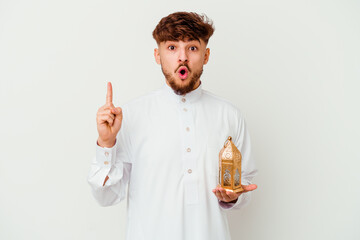 Young Moroccan man wearing a typical arab clothes holding a ramadan lamp isolated on white background having some great idea, concept of creativity.