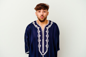 Young Moroccan man isolated on white background shrugs shoulders and open eyes confused.