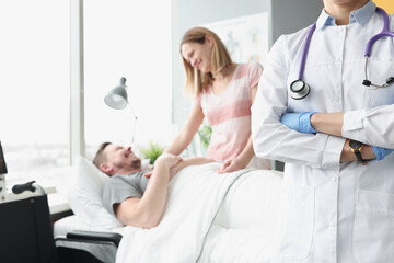 Fototapeta premium Happy man lies on hospital bed his hand is held by woman next to doctor