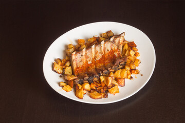 Dinner plate presentation of pork ribs cooked in a spicy vegetable sauce on a white plate. Tasty homemade meat recipes.