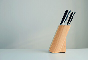 set of knives on a wooden stand on a white background, copy space