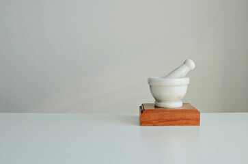 Mortar and pestle made of white stone on a wooden stand. Stylish interior mockup, copy space.
