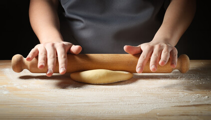 Obraz na płótnie Canvas Egg pasta, young woman hands working the dough with rolling pin on pastry board, closeup, copy space.