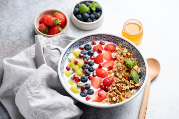 Yogurt granola bowl with berries strawberries pomegranate kiwi fruit blueberries closeup view. Healthy breakfast cereal granola bowl