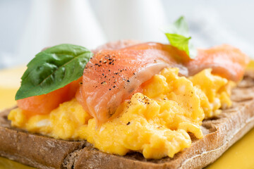 Scrambled egg and smoked salmon on a rye bread toast, closeup view. English breakfast food